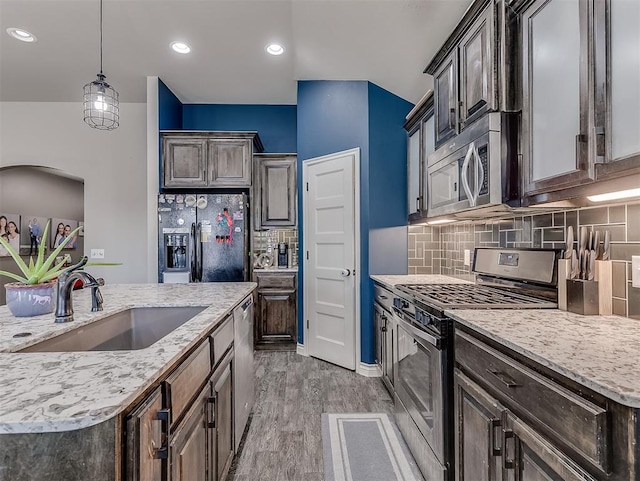 kitchen with sink, stainless steel appliances, dark brown cabinets, and light hardwood / wood-style floors