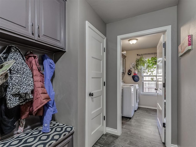 clothes washing area with washer and clothes dryer, cabinets, and hardwood / wood-style flooring