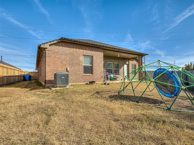 rear view of house with central air condition unit and a yard