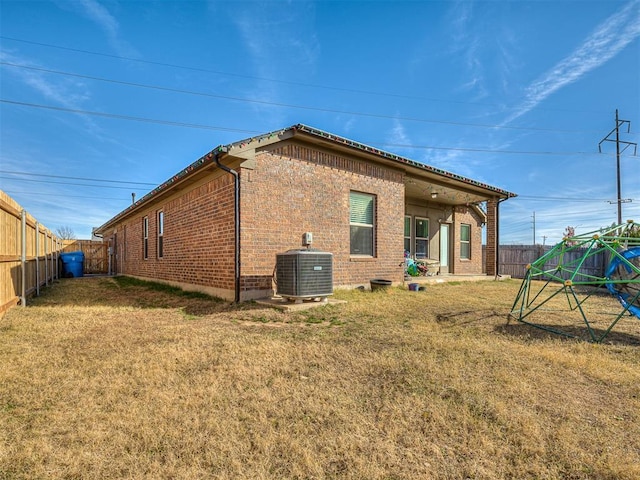 back of property with central AC unit and a lawn