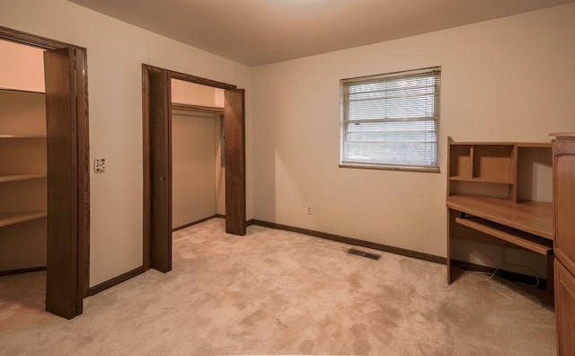 unfurnished bedroom with a closet and light colored carpet