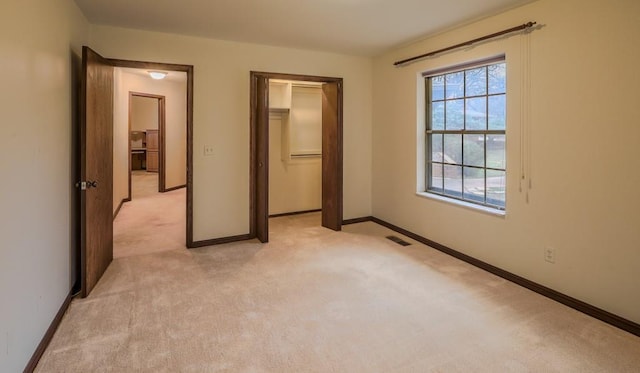 unfurnished bedroom with light colored carpet, a spacious closet, and a closet