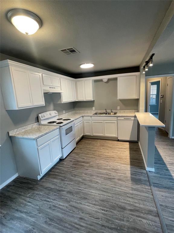 kitchen featuring dark wood-type flooring, sink, white electric stove, stainless steel dishwasher, and white cabinetry