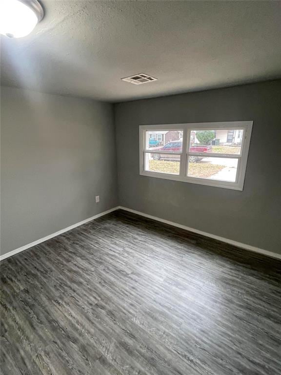 spare room featuring dark hardwood / wood-style flooring and a textured ceiling