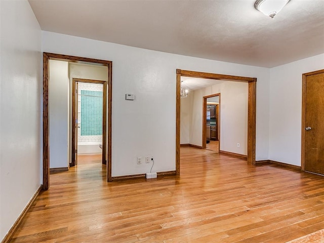 empty room with a chandelier and light hardwood / wood-style floors