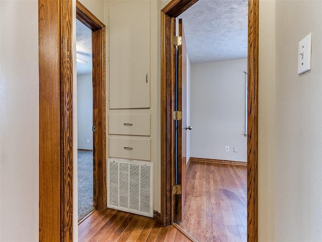 hallway featuring hardwood / wood-style floors and a textured ceiling