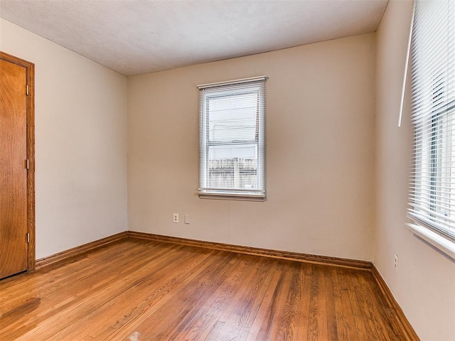 empty room with a textured ceiling and light hardwood / wood-style flooring