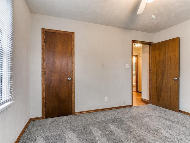 unfurnished bedroom with ceiling fan, light carpet, and a textured ceiling