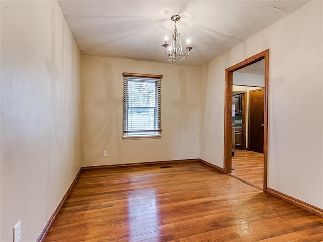 unfurnished room with hardwood / wood-style flooring and a notable chandelier