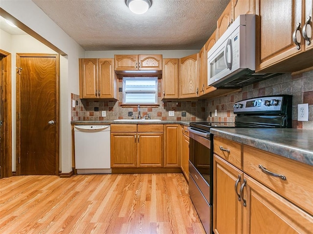 kitchen featuring sink, light hardwood / wood-style flooring, a textured ceiling, white appliances, and decorative backsplash