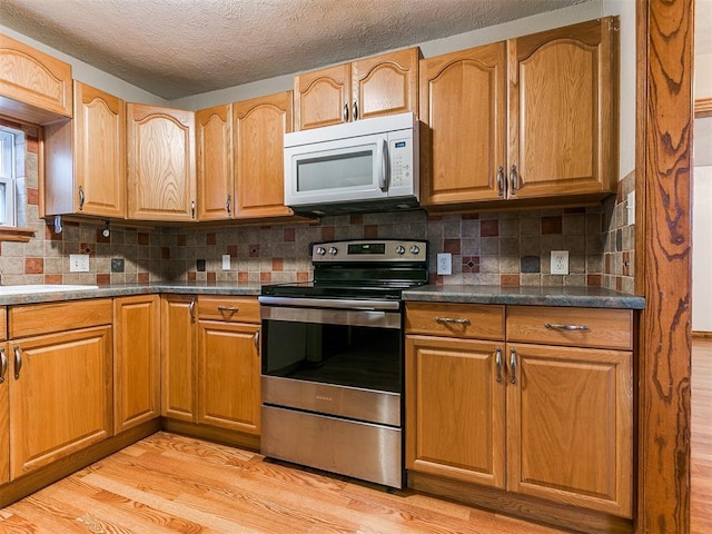 kitchen with electric stove, decorative backsplash, light hardwood / wood-style flooring, and a textured ceiling