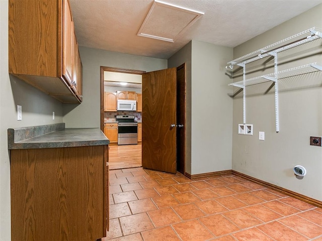 interior space with hookup for a washing machine, a textured ceiling, and hookup for an electric dryer