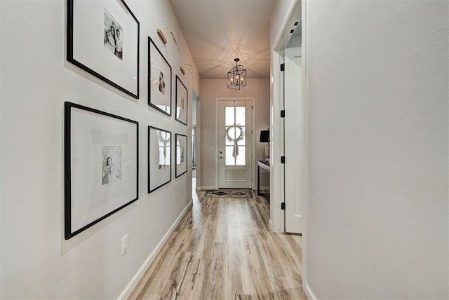 doorway to outside with light hardwood / wood-style flooring and a notable chandelier