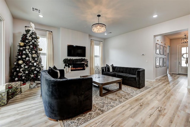 living room featuring light wood-type flooring and an inviting chandelier