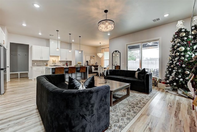 living room with a chandelier and light wood-type flooring