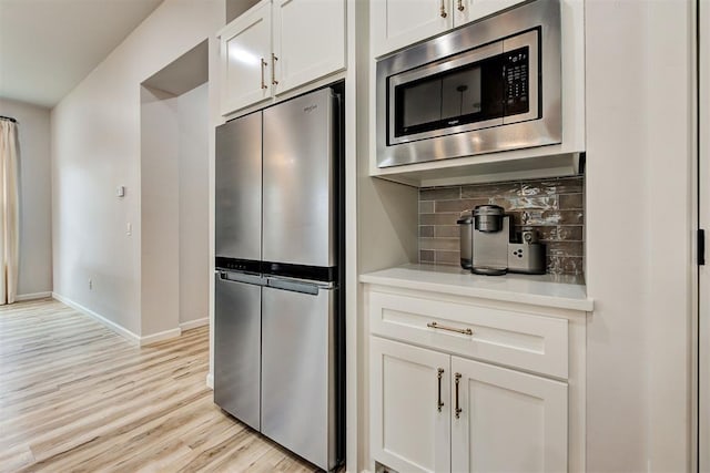 kitchen featuring light hardwood / wood-style floors, white cabinetry, backsplash, and appliances with stainless steel finishes