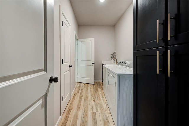 clothes washing area featuring washer and dryer, light hardwood / wood-style floors, and cabinets