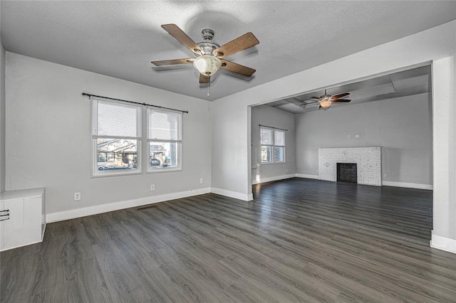 unfurnished living room featuring dark hardwood / wood-style floors, a healthy amount of sunlight, a textured ceiling, and a brick fireplace