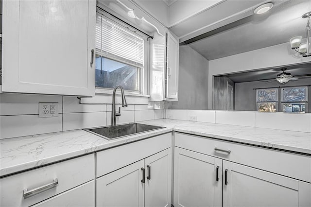 kitchen featuring white cabinetry, sink, ceiling fan, light stone countertops, and decorative backsplash