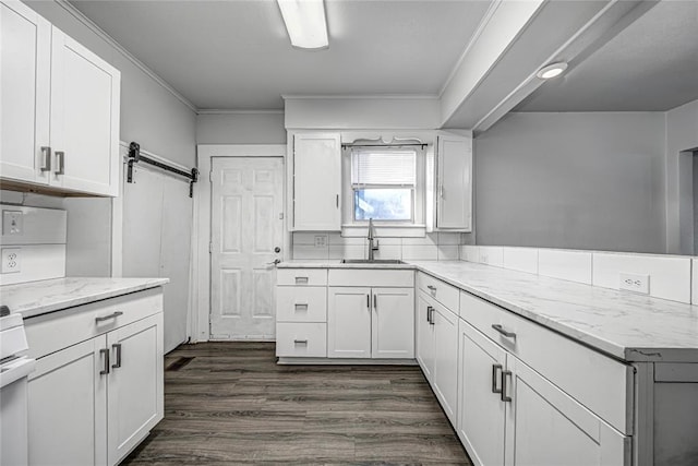 kitchen featuring white cabinetry, sink, a barn door, dark hardwood / wood-style floors, and crown molding