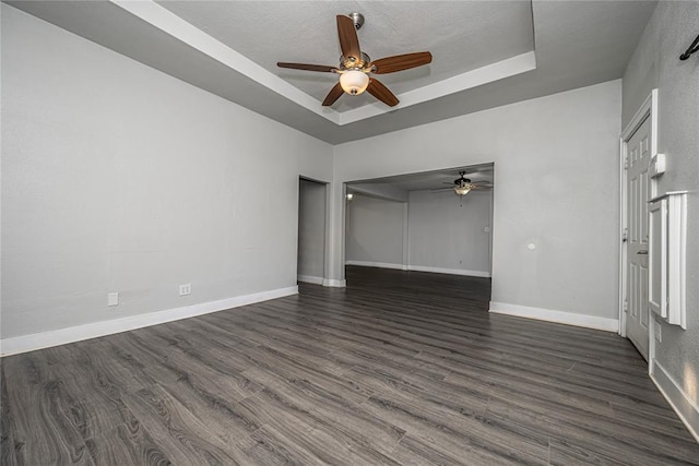 empty room featuring a tray ceiling and dark hardwood / wood-style floors