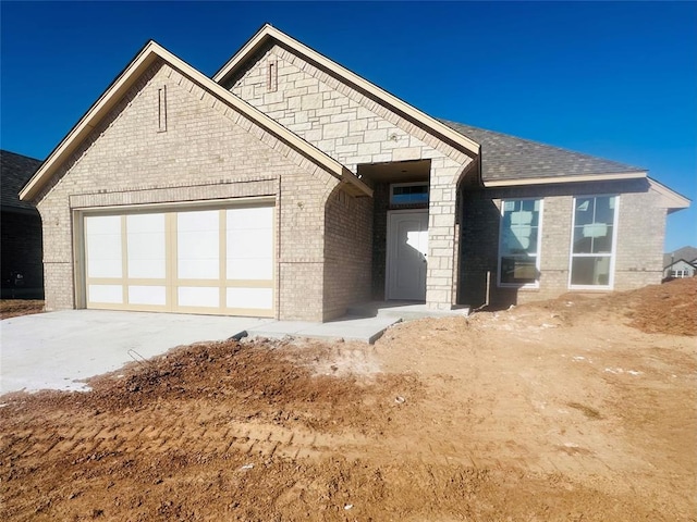 view of front of property with concrete driveway, an attached garage, brick siding, and roof with shingles