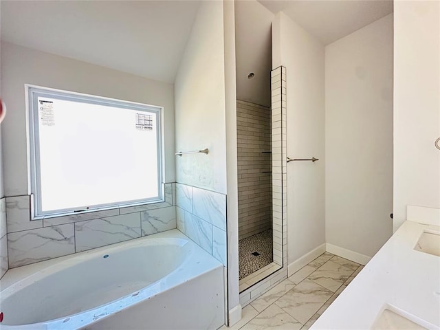 bathroom with baseboards, lofted ceiling, a tile shower, a bath, and marble finish floor