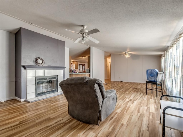 living room with ceiling fan, light hardwood / wood-style floors, and a textured ceiling