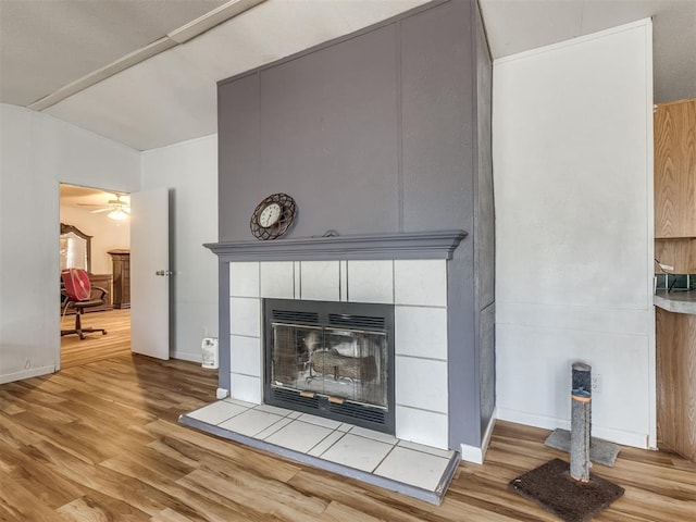 details with a tiled fireplace, ceiling fan, and hardwood / wood-style floors