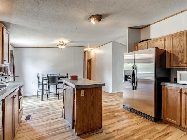 kitchen featuring a textured ceiling, light hardwood / wood-style floors, crown molding, and stainless steel refrigerator with ice dispenser