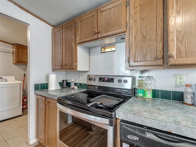 kitchen with stainless steel electric stove, light tile patterned floors, black dishwasher, a textured ceiling, and washer / dryer