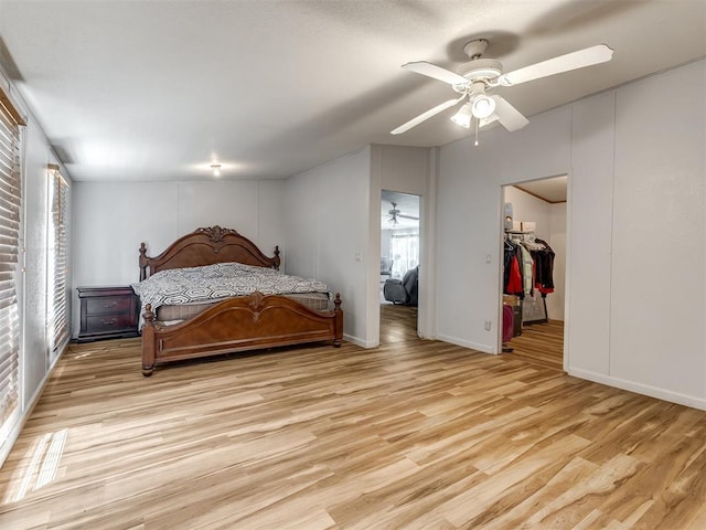 bedroom featuring a spacious closet, ceiling fan, light wood-type flooring, and a closet