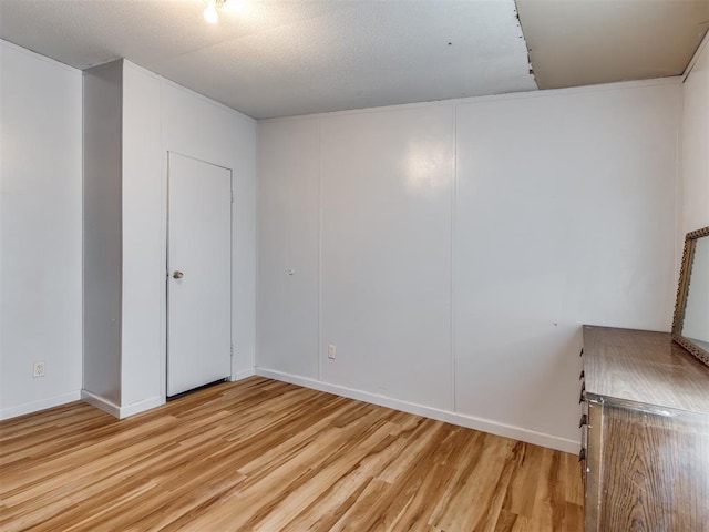 unfurnished room featuring a textured ceiling and light hardwood / wood-style flooring