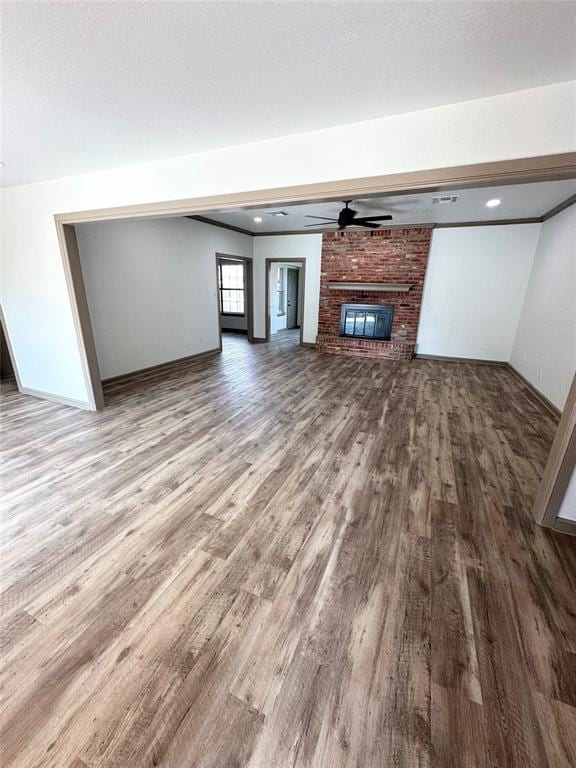 unfurnished living room featuring hardwood / wood-style flooring, a brick fireplace, and ceiling fan