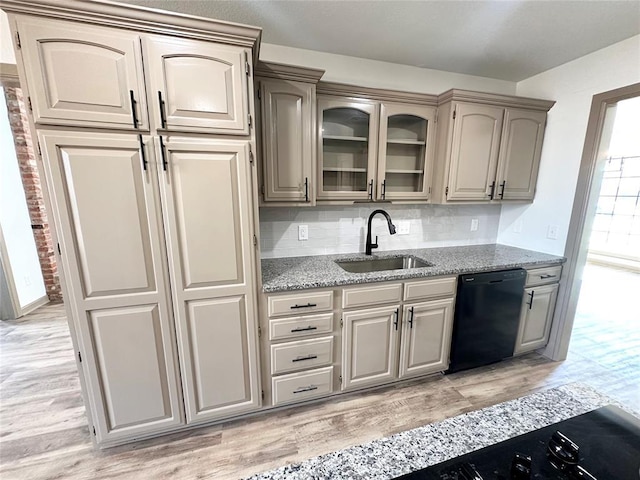 kitchen featuring decorative backsplash, sink, light wood-type flooring, and black dishwasher