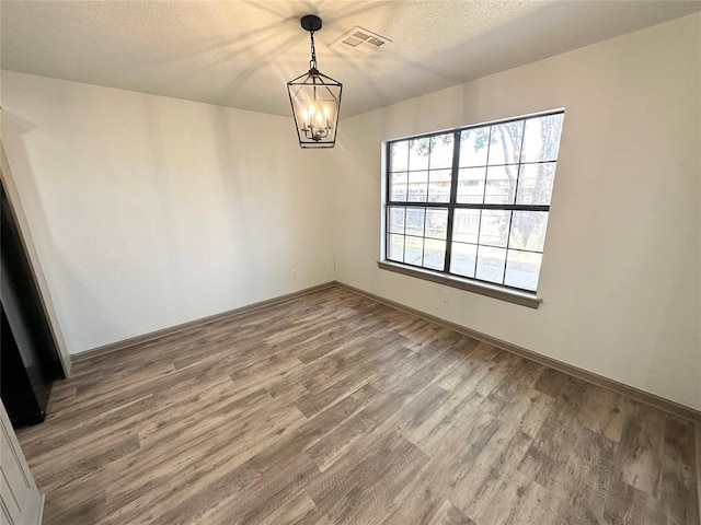 unfurnished dining area with wood-type flooring and an inviting chandelier