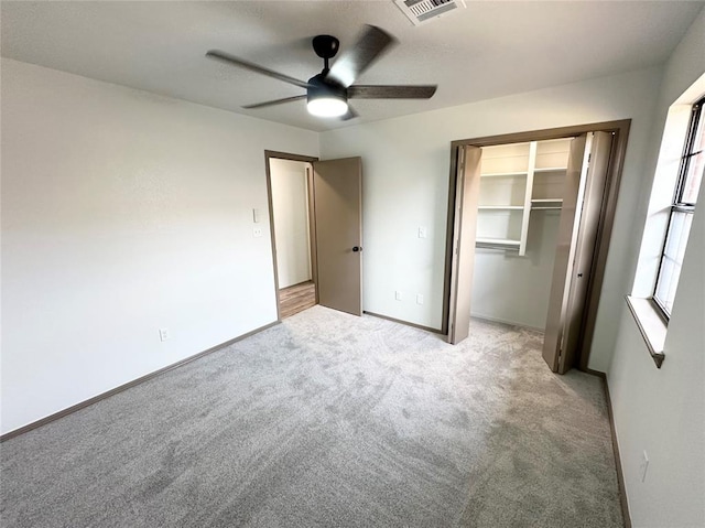 unfurnished bedroom featuring ceiling fan, a closet, and light carpet