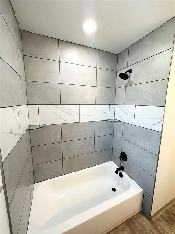 bathroom with hardwood / wood-style flooring and tiled shower / bath