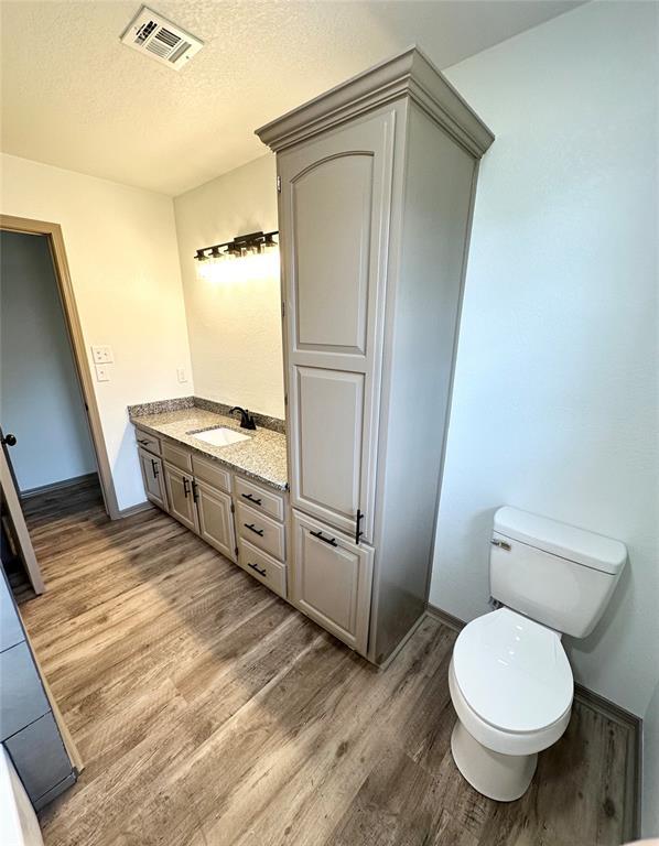 bathroom with vanity, toilet, wood-type flooring, and a textured ceiling