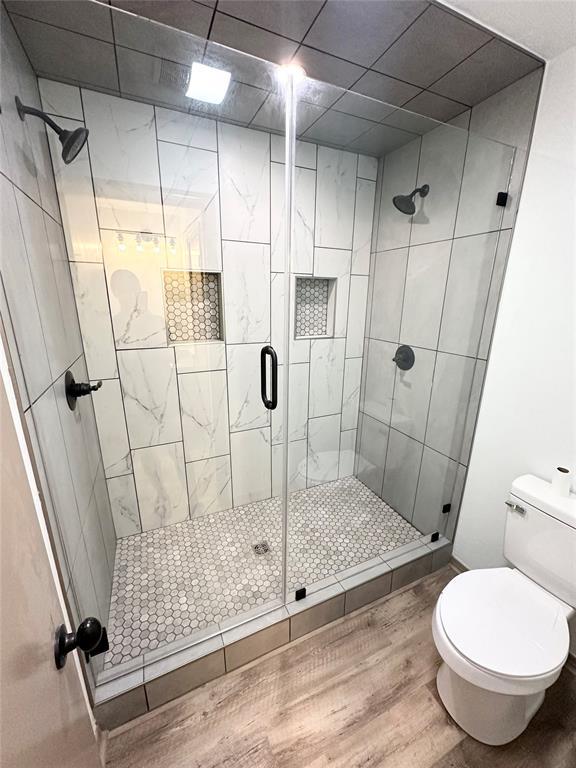 bathroom featuring hardwood / wood-style flooring, toilet, and a shower with door