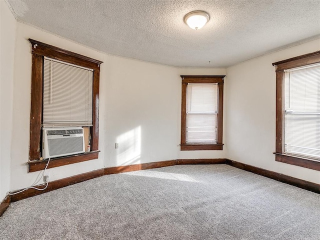 spare room featuring cooling unit, carpet, and a textured ceiling