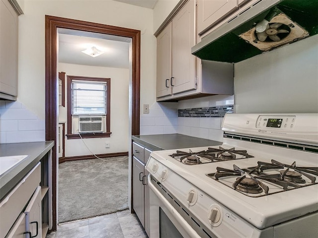 kitchen with white gas stove, backsplash, cooling unit, gray cabinets, and light carpet