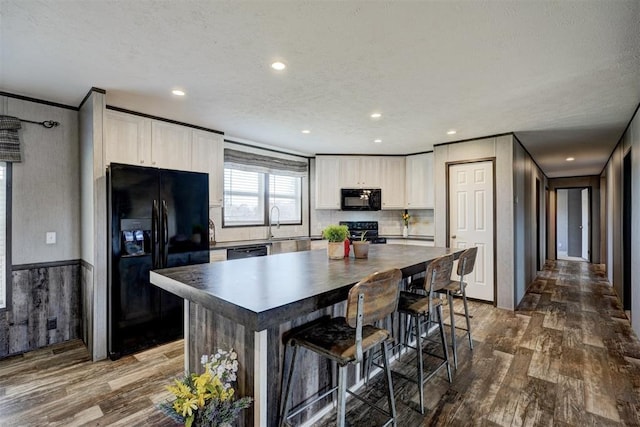 kitchen featuring white cabinetry, dark hardwood / wood-style flooring, a textured ceiling, a kitchen island, and black appliances