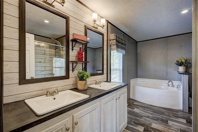 bathroom with vanity, a textured ceiling, wooden walls, hardwood / wood-style flooring, and plus walk in shower