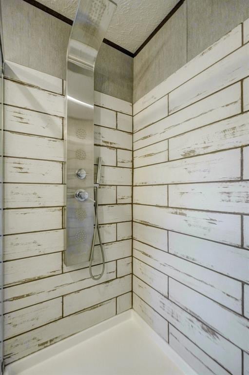 bathroom with wood walls, a textured ceiling, and walk in shower