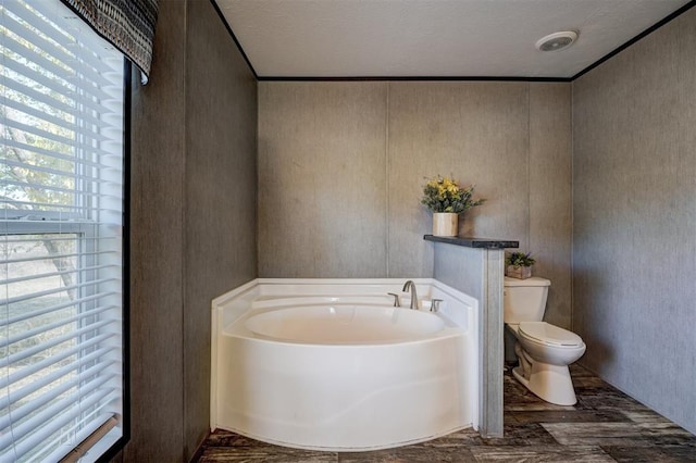 bathroom featuring a bathing tub, crown molding, toilet, and a textured ceiling