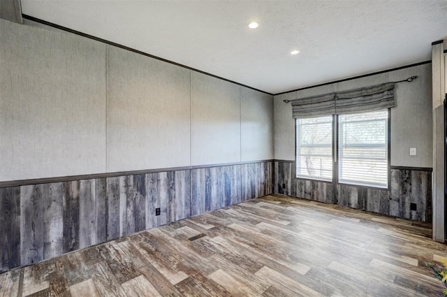 spare room featuring wood walls and light hardwood / wood-style flooring