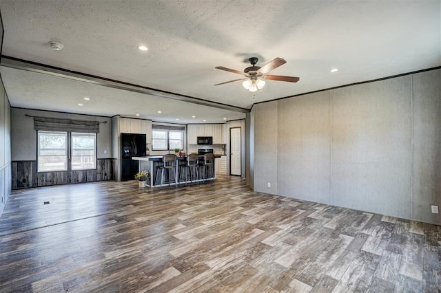 unfurnished living room with ceiling fan, wood-type flooring, a textured ceiling, and a wealth of natural light