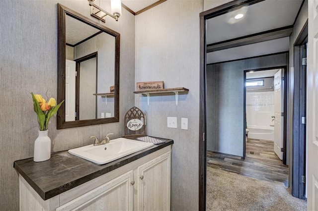 bathroom featuring hardwood / wood-style floors, vanity, and ornamental molding