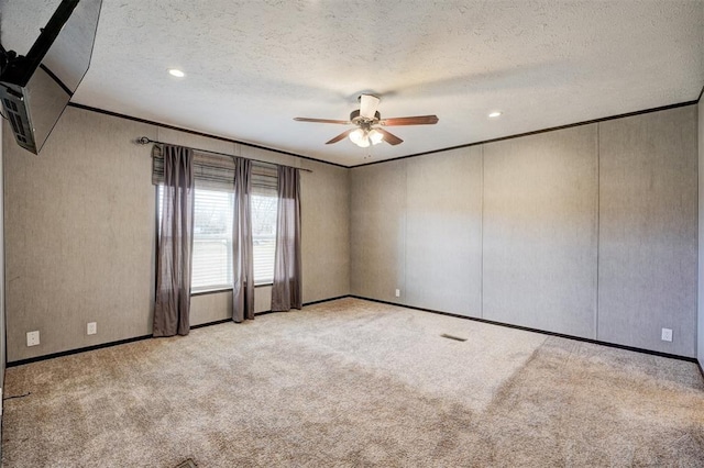 spare room featuring ceiling fan, crown molding, light colored carpet, and a textured ceiling